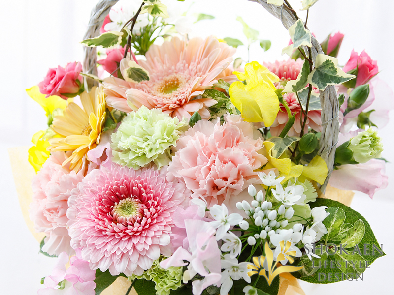 alt="可憐なフラワーギフト 全国発送！金沢正花園の淡いピンクや黄色が優しく持ち手付きカゴにグリーンが絡む愛らしいアレンジメント"